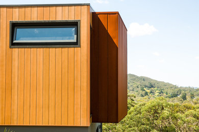 Photo of a large and brown contemporary two floor detached house in Wollongong with metal cladding, a flat roof and a metal roof.