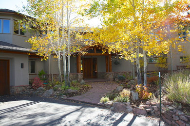Example of a large mountain style beige two-story stucco exterior home design in Denver with a shingle roof