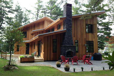 Inspiration pour une façade de maison marron chalet en bois de taille moyenne et à un étage avec un toit à deux pans et un toit en métal.