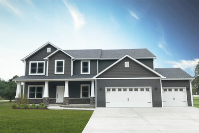 Imagen de fachada de casa gris grande de dos plantas con revestimiento de vinilo y tejado de teja de madera