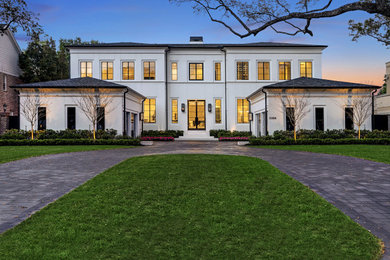 Huge transitional white two-story house exterior idea in Houston with a clipped gable roof and a shingle roof