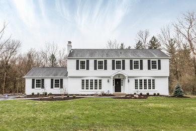 Imagen de fachada de casa blanca clásica de dos plantas con tejado de teja de madera