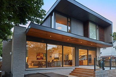 Imagen de fachada de casa gris minimalista grande de dos plantas con revestimientos combinados y tejado plano
