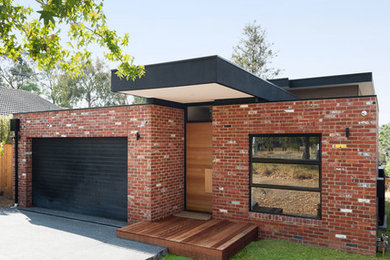 Imagen de fachada de casa moderna de dos plantas con revestimiento de ladrillo, tejado plano y tejado de metal