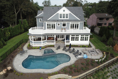 Inspiration for a large gray three-story vinyl exterior home remodel in New York with a mixed material roof