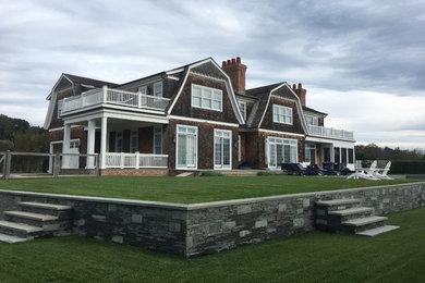 Large elegant brown two-story wood house exterior photo in New York with a gambrel roof and a shingle roof