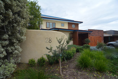 Foto de fachada de casa beige mediterránea de tamaño medio de dos plantas con revestimiento de madera, tejado plano y tejado de metal