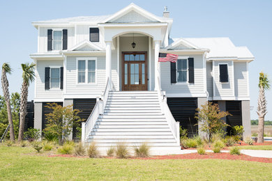 Exemple d'une façade de maison grise bord de mer avec un toit en métal.
