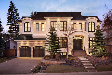 Transitional beige two-story stucco house exterior idea in Calgary with a gambrel roof and a shingle roof
