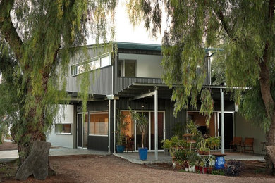 Diseño de fachada de casa gris contemporánea de dos plantas con revestimiento de metal y tejado de metal