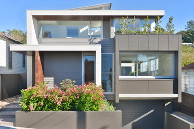Inspiration pour une façade de maison marron design de taille moyenne et à un étage avec un revêtement mixte, un toit plat et un toit en métal.