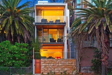Mid-sized trendy white three-story concrete exterior home photo in Sydney with a metal roof