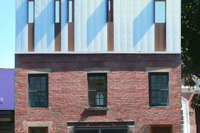 Mittelgroßes, Zweistöckiges Industrial Einfamilienhaus mit Mix-Fassade, roter Fassadenfarbe, Flachdach und Blechdach in New York