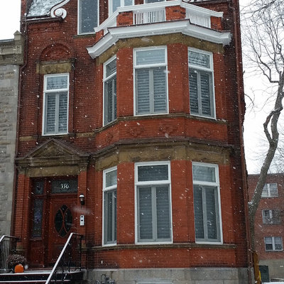 Inspiration for a large timeless red three-story brick gable roof remodel in Montreal