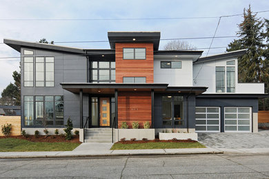 Aménagement d'une grande façade de maison grise contemporaine à un étage avec un revêtement mixte et un toit plat.