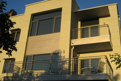Ejemplo de fachada beige moderna de tamaño medio de dos plantas con revestimiento de estuco y tejado plano
