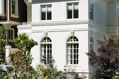 Imagen de fachada blanca clásica grande de tres plantas con revestimiento de estuco