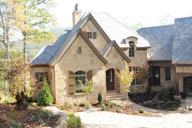 Large craftsman beige two-story stone house exterior idea in Nashville with a hip roof and a shingle roof