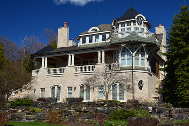 Ejemplo de fachada de casa beige tradicional extra grande de tres plantas con revestimiento de piedra, tejado a dos aguas y tejado de teja de barro