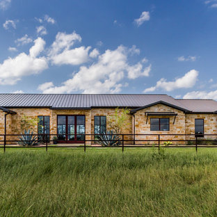 Example of a farmhouse brown one-story stone exterior home design in Dallas with a metal roof