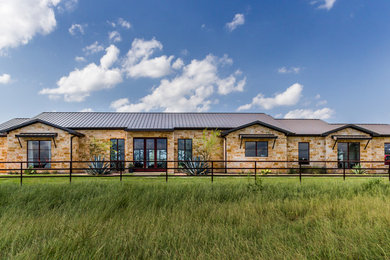 Example of a farmhouse brown one-story stone exterior home design in Dallas with a metal roof