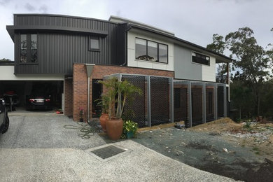 Inspiration for a contemporary two floor house exterior in Brisbane with metal cladding.