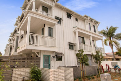 This is an example of a medium sized and white beach style flat in San Diego with three floors, concrete fibreboard cladding and board and batten cladding.