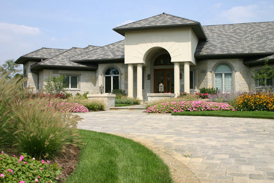 Exemple d'une grande façade de maison beige tendance en pierre à un étage avec un toit à quatre pans.