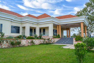Diseño de fachada de casa beige actual grande de una planta con revestimiento de vinilo, tejado a cuatro aguas y tejado de teja de barro