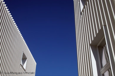 Imagen de fachada blanca moderna de tamaño medio de tres plantas con revestimientos combinados y tejado plano