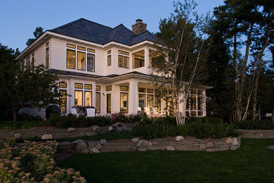Inspiration for a large timeless white two-story vinyl house exterior remodel in Other with a shed roof