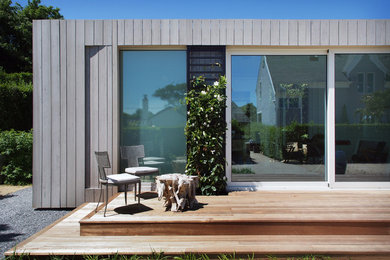 Esempio della facciata di una casa piccola grigia moderna a un piano con rivestimento in legno e tetto piano