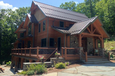 Example of a large mountain style brown three-story wood exterior home design in New York with a metal roof
