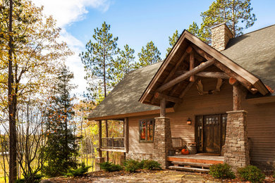 Exemple d'une grande façade de maison beige montagne en bois de plain-pied avec un toit à quatre pans.