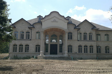 Expansive and gey mediterranean two floor house exterior in Toronto with stone cladding.
