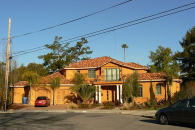 Imagen de fachada de casa naranja mediterránea grande de dos plantas con revestimiento de estuco, tejado a dos aguas y tejado de teja de barro