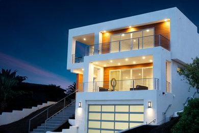 Ejemplo de fachada blanca minimalista grande de tres plantas con revestimiento de estuco y tejado plano
