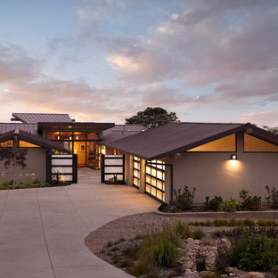 This is an example of a medium sized and beige contemporary one floor render detached house in Los Angeles with a pitched roof and a metal roof.