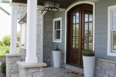 Ejemplo de fachada de casa gris de estilo americano de dos plantas con revestimientos combinados