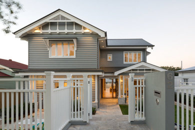 Medium sized and gey traditional two floor house exterior in Brisbane with wood cladding and a pitched roof.