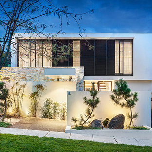 Modelo de fachada blanca, minimalista, de dos plantas, con revestimientos combinados y tejado plano