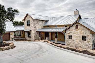 Aménagement d'une grande façade de maison beige classique en pierre à un étage avec un toit à deux pans.