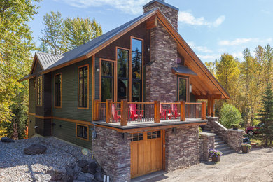 Example of a mid-sized mountain style green two-story wood gable roof design in Calgary