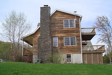 Diseño de fachada marrón tradicional de tamaño medio de dos plantas con revestimiento de madera y tejado a dos aguas