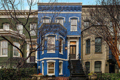 Foto della facciata di una casa a schiera ampia blu a tre piani con rivestimento in mattoni e copertura mista