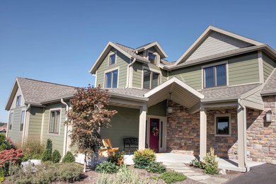 Cette image montre une grande façade de maison verte craftsman à deux étages et plus avec un revêtement mixte et un toit à deux pans.