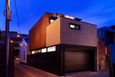 Réalisation d'une petite façade de maison noire minimaliste en béton à un étage avec un toit à deux pans.
