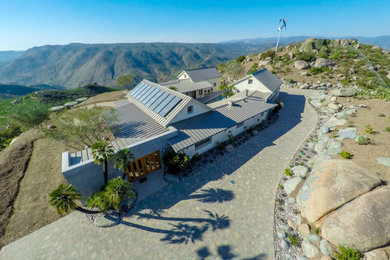 Example of a cottage one-story stucco house exterior design in San Diego with a metal roof