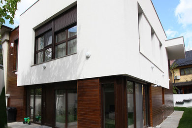Example of a small trendy white two-story concrete exterior home design in Other