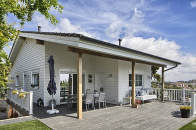 Modelo de fachada blanca de estilo de casa de campo grande de dos plantas con revestimiento de madera y tejado a dos aguas